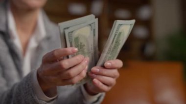 Üst düzey bir kadının ABD Doları 'na ait nakit paraları sayması, mali işlemleri ve kişisel finansmanı gösteren yakın plan fotoğrafları..