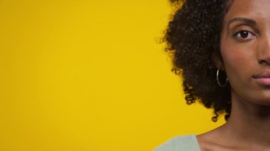 Kadın yüzünün sanatsal yakın çekimi ve kıvırcık saçlı, parlak sarı arkaplan, kontrast ve ayrıntıları vurguluyor..