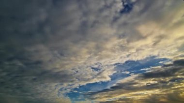 Gün batımında dramatik bulutların dinamik zaman çizelgesi, altın rengi ve mavi gökyüzü sakin bir atmosfer yaratıyor..