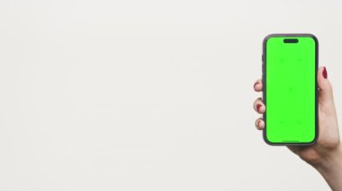 Parlak yeşil ekranlı akıllı telefonu tutan bir elin yakın çekimi, uygulama tasarımı ya da ürün modellemeleri için mükemmel..