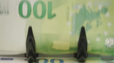 Para sayma makinesi tarafından yönetilen 100 avroluk banknotların kapatılması, mali işlemleri ve para birimi doğrulamasını simgeliyor.