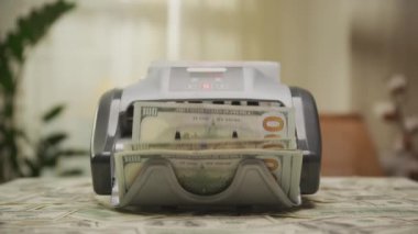 Para sayacında 100 dolarlık banknotların dramatik zoom çekimi, zenginlik, finansal işlemler ve nakit akışı yönetimi vurgulanıyor.
