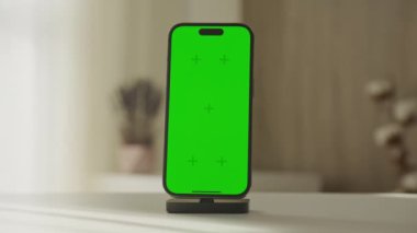 Yanaşma istasyonuna yeşil ekran yerleştirilmiş akıllı telefonun yakın plan görüntüsü, modelleme veya uygulama sunumları için ideal.