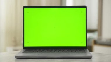 Yumuşak ışıklandırılmış çalışma alanına ayarlanmış canlı yeşil ekran krom anahtarı olan bir dizüstü bilgisayarın statik ön görüntüsü.