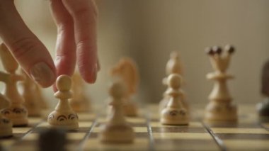 Oyunda strateji ve karar verme mekanizmasını sembolize eden, satranç tahtasındaki tahta piyonu hareket ettiren bir elin yakın çekimi.