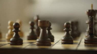 Satranç taşlarının yörüngesinde dönen dinamik, tahta satranç tahtasındaki bir kaleye ve piyonlara odaklanıyor, stratejiyi sembolize ediyor ve odaklanıyor..