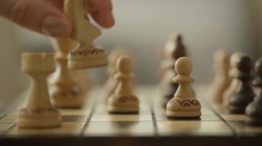 Satranç tahtasındaki tahta şövalyeyi stratejik olarak hareket ettiren bir elin detaylı yakın çekimi karar verme mekanizmasını ve stratejiyi sembolize ediyor..