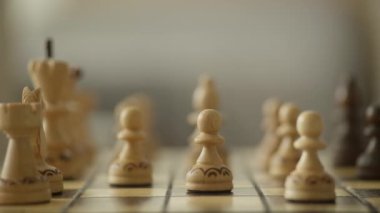 Satranç tahtasındaki ahşap satranç taşlarının detaylı bir görüntüsü, yüzeysel alan derinliği odaklanmış ve sanatsal bir kompozisyon oluşturuyor..