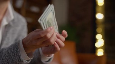 Bir kadının elleri, zenginliği, finansal başarıyı ve refahı sembolize eden 100 dolarlık banknotların büyük bir yığını..