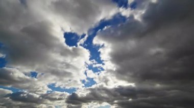Karanlık ve aydınlık bulutların çarpıcı görüntüsü gökyüzünü dolduruyor, boşluklardan görünen mavi lekeler, dramatik bir atmosfer zaman çizelgesi yaratıyor..
