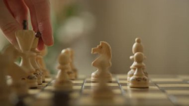 Bir el veziri tahta bir satranç tahtasına oturturken stratejik bir satranç hamlesi yapılıyor. Klasik Queen Gambit açılışını gösteriyor..
