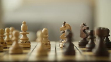 Bir satranç tahtasının sinematik çekimleri, ön plan ve arka plan arasında kayan derinlik, tahta satranç taşlarının stratejik konumlarını vurguluyor..