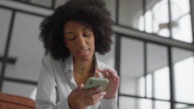 Hayal kırıklığına uğramış bir genç kadın akıllı telefonuna bakıyor, modern ortamlarda online alışveriş yaparken ürünleri değerlendiriyor..