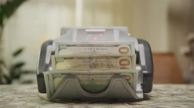 100 dolarlık banknotları işleyen, finans, bankacılık, zenginlik ve nakit akışını sembolize eden para sayma makinesinin dinamik bir görüntüsü..