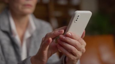 Üst düzey bir kadının akıllı bir telefonla el ele tutuşması ve etkileşimi, modern teknoloji kullanımı ve bağlantısını vurguluyor..