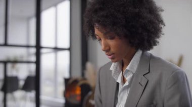 Takım elbiseli profesyonel bir kadın modern bir ofiste dizüstü bilgisayarı üzerinde çalışırken verimliliği, teknolojiyi ve ticareti sembolize ediyor..