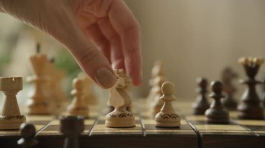 Satranç oyunu sırasında tahta şövalyeyi hareket ettiren bir elin yakın çekimi strateji, zeka, karar verme ve rekabeti sembolize eder..