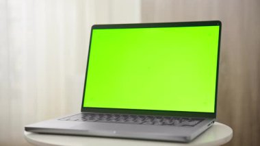 Modern bir dizüstü bilgisayarın dramatik bir yakınlaştırma görüntüsü. Yeşil ekranlı. Yumuşak ışıklı bir odada beyaz bir masaya yerleştirilmiş..