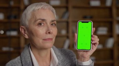 Yeşil ekranlı akıllı telefonu elinde tutan neşeli bir son sınıf öğrencisi. Model, uygulama sunumları ya da dijital içerik özelleştirmesi için mükemmel..