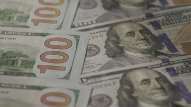 Benjamin Franklins 'in portresi ve finansal güvenlik özelliklerinin sergilendiği, zenginlik ve ekonomiyi sembolize eden birden fazla yüz dolarlık banknotların detaylı bir yakın çekimi..