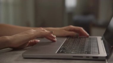 Dizüstü bilgisayarı kullanarak, rahat bir iç mekanda internette gezinen, tanınmayan kadın kollarının çekimleri..