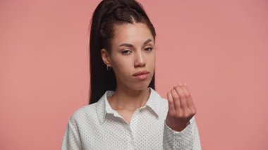 Etkilenmemiş kadın, klasik parmak hareketleriyle elini kaldırarak pembe arka planda izole bir şekilde para ya da ödeme istiyor..