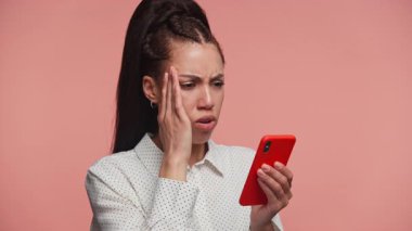 Genç kadın endişeli bir ifadeyle akıllı telefonu tutuyor, mobil bir uygulama kullanırken beklenmedik ya da olumsuz haberlere tepki veriyor.