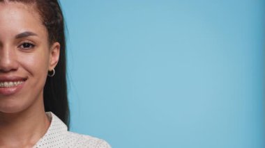 Tel takan gülümseyen genç bir kadının kısmi yüzü, sağ tarafta geniş bir kopya alanı olan canlı mavi bir arkaplan üzerine çekilmiş..