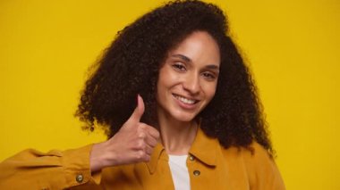 Parlak sarı arka planda gülümseyen mutlu bir genç kadın.