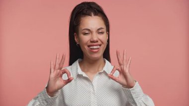 Puantiyeli tişörtlü gülümseyen genç kadın, bir ürünü veya servisi değerlendirir gibi memnuniyetini belirterek el hareketlerini iki kat onaylıyor..