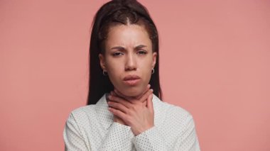 Benekli tişörtlü endişeli genç kadın iki eliyle boynunu sıkıyor. Boğaz ağrısı, boğulma ya da sağlık sorunu olduğunu gösteriyor..