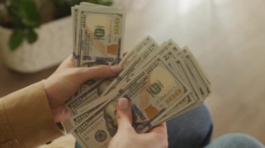 Para akışını, zenginliği veya finansal planlamayı sembolize eden kalın bir deste 100 'lük banknotun el ele tutuşması ve tasnif edilmesi..