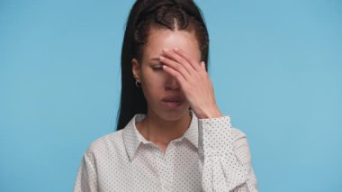 Endişeli genç bir kadın hayal kırıklığı içinde, maddi sıkıntılar ya da mavi arka planda yaşam zorlukları yaşıyor..