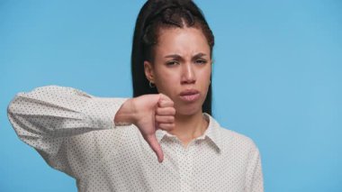 Ciddi genç bir kadın hayal kırıklığına uğramış bir ifadeyle, mavi bir arka planda memnuniyetsizlik ya da hoşnutsuzluk sinyalleri veriyor..