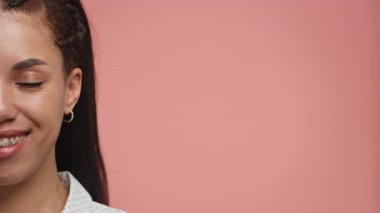 Gülümseyen genç bir kadının kesilmiş portresi, diş telleri görünür, fotokopi alanı için düz pembe bir arka plan üzerine kurulmuş..