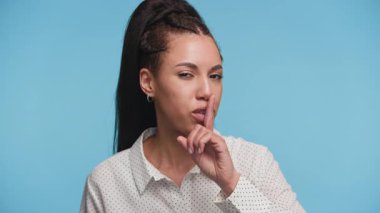 Gülümseyen genç bir kadın, parmaklarıyla dudaklarında 