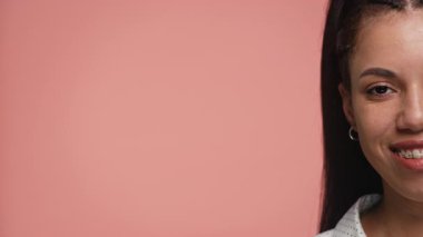 Yüzünün yarısını fotokopi için pembe bir arka planda gösteren, diş telli, gülümseyen bir kadının aşırı yakın plan portresi..