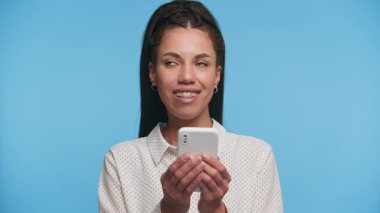 Akıllı telefonu tutan ve hafifçe gülümseyen düşünceli bir kadının portresi, göndermeden önce mesajını dikkate alarak..