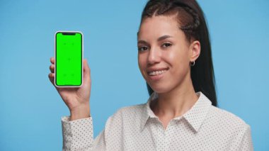 Kendine güvenen genç bir kadın elinde yeşil ekran ekranlı akıllı telefonu tutuyor. Uygulama modeli ya da tanıtım içeriği eklemeye hazır..