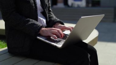 Dışarıda dizüstü bilgisayarda çalışan, uzaktan çalışma ya da serbest çalışma sırasında klavyede doğal ışık altında yazan olgun profesyonel bir kadın..