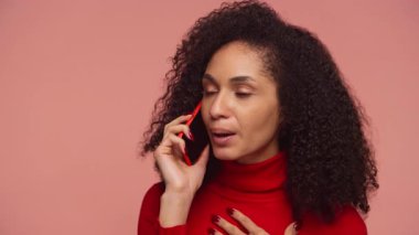 Kırmızı kazaklı mutlu kadın kulağına akıllı telefon dayayıp pembe arka plandaki telefon görüşmesinde neşeli bir konuşma yapıyor..