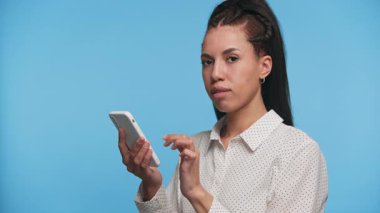 Neşeli genç bir kadın elinde akıllı telefon, internette geziniyor, dijital içerikten ya da sosyal medyadan keyif alıyor..