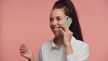 Gülümseyen kadın hoş bir telefon konuşması yapıyor, pembe arka planda duruyor, cep telefonuyla neşe ve bağlantı kuruyor..