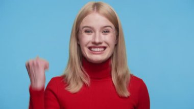 Kırmızı balıkçı yakalı mutlu genç kadın gülümsedi ve kutlama için yumruğunu sıktı. Başarı ve heyecanı ifade etti..