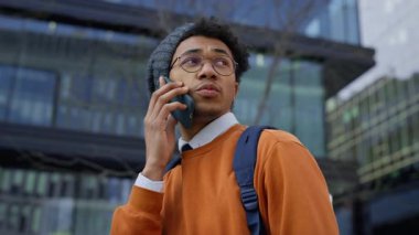 Sırt çantası ve beresi olan ciddi görünümlü bir üniversite öğrencisi şehir merkezinde telefon görüşmesi yapıyor, muhtemelen önemli haberler alıyor..