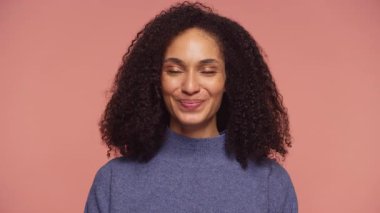 Mutabakat içinde gülümseyen bir öğrencinin portresi, olumlu duygular ve onay göstererek sağlam pembe bir arka plana karşı.