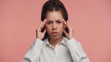 Gözleri kapalı genç bir kadın tapınakları sıkıştırıyor, acı ve rahatsızlığını ifade ediyor ya da pembe arka planda yoğun bir stres yaşıyor..