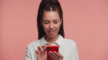 Diş teli takan genç bir kadın akıllı telefonundaki beklenmedik bir mesaja hevesle tepki veriyor. Gözleri şaşkınlıkla açık..