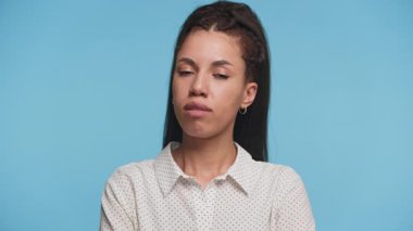 Ciddi bir kadın mavi arka planda dikilirken onaylamak ya da onaylamak için başını sallıyor..