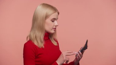 Kırmızı kazaklı sarışın kadın hesap makinesi kullanıyor. Pembe arka planda, mali ya da eğitimsel konseptte izole edilmiş.